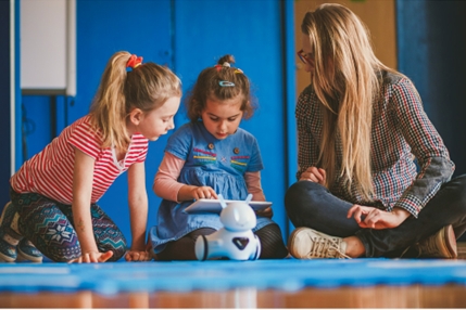 Kinder mit Roboter und Tablet auf dem Boden kniend