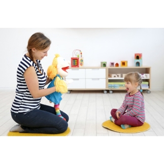 Erzieherin mit Therapeutischer Handpuppe Lena lobt ein Mädchen, beide am Boden sitzend