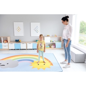 kleines Mädchen steht auf einem Teppich mit Sonne und wird von der Erzieherin gelobt