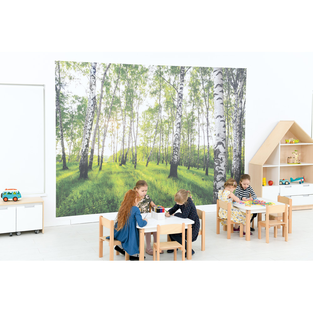 Kinder sitzen an Tischen im Gruppenraum, lernen und spielen.