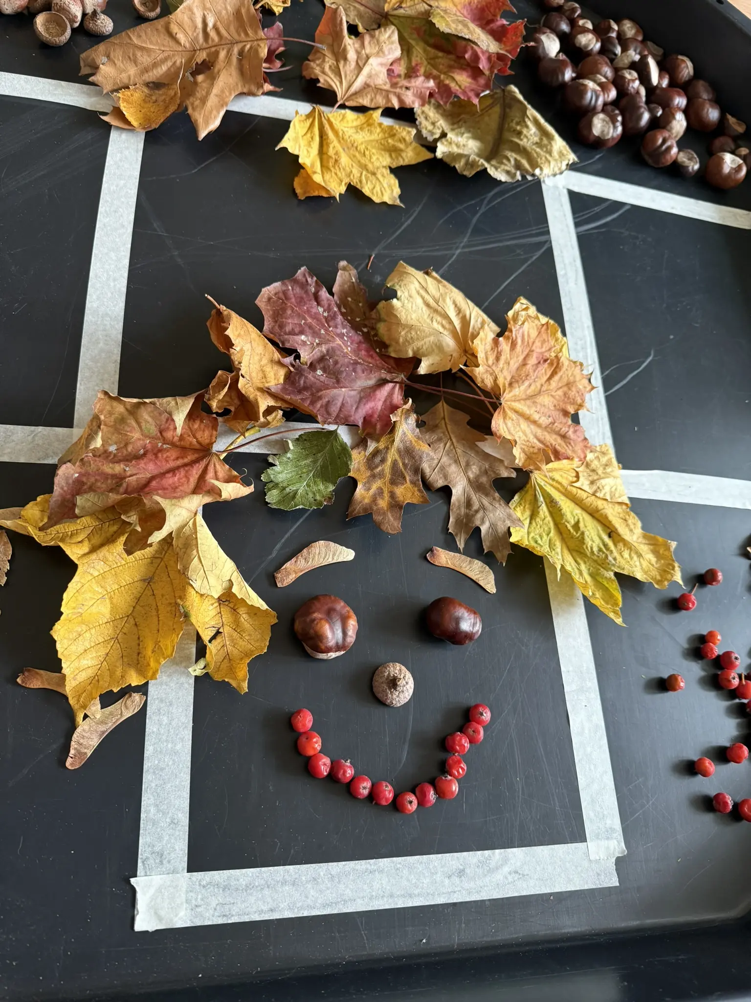 Kinder legen aus Herbstmaterialien Gesichter in verschiedenen Stimmungen