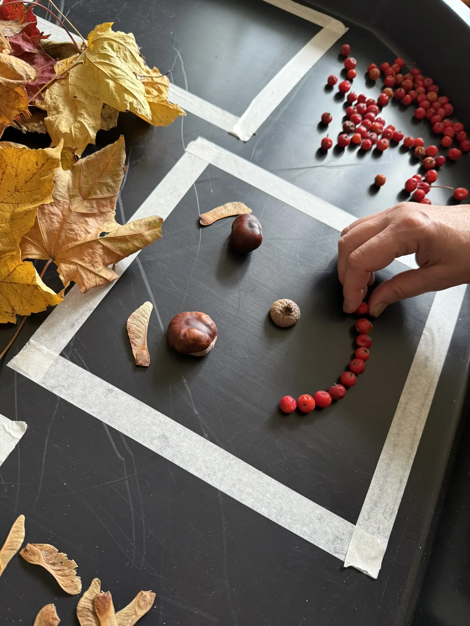Kinder legen aus Herbstmaterialien Gesichter in verschiedenen Stimmungen