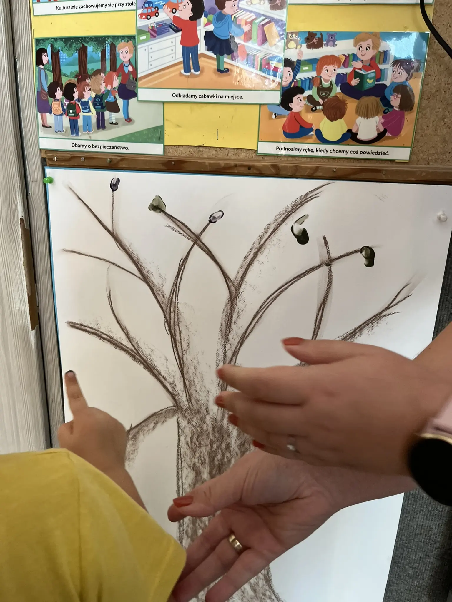 Ein gemalter Baum auf einem großen Blatt erhält bunte Blätter aus Fingerfarben
