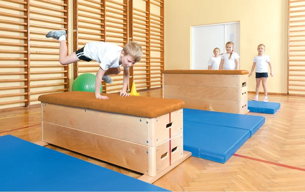 Kinder üben an Sportgeräten wie Sprungkästen oder Turnböcken ihre Sprungkraft und Koordination