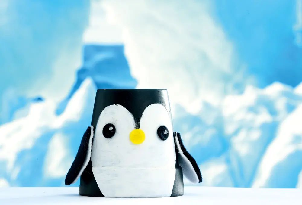 Tontopf-Pinguin vor einem winterlichen Hintergrund