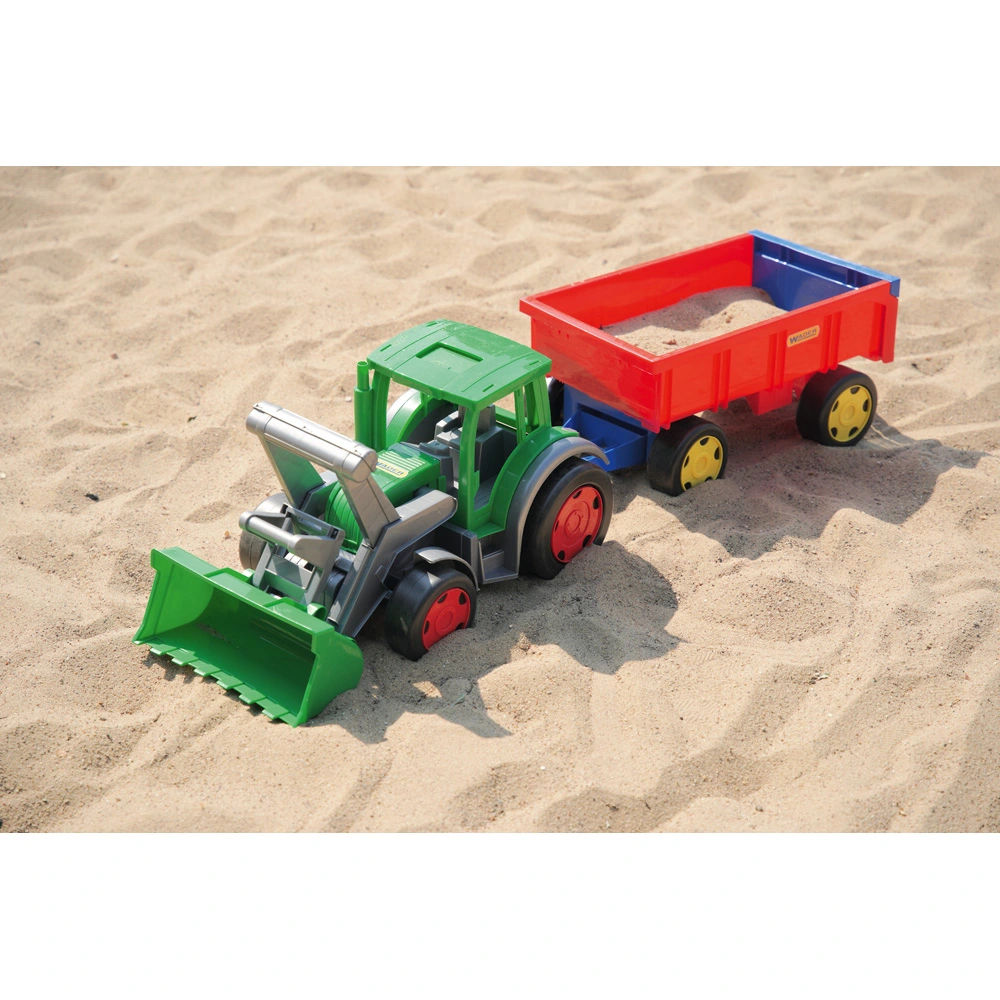 Ein Spielzeugbagger und ein mit Sand gefüllter Anhänger stehen in einem großen Sandkasten.
