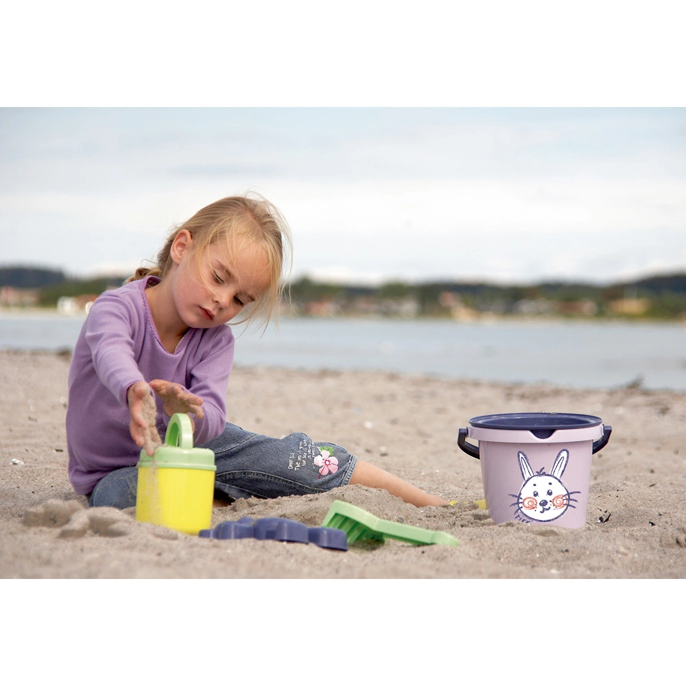 Ein Kind spielt am Strand mit Schippe, Eimer und Förmchen