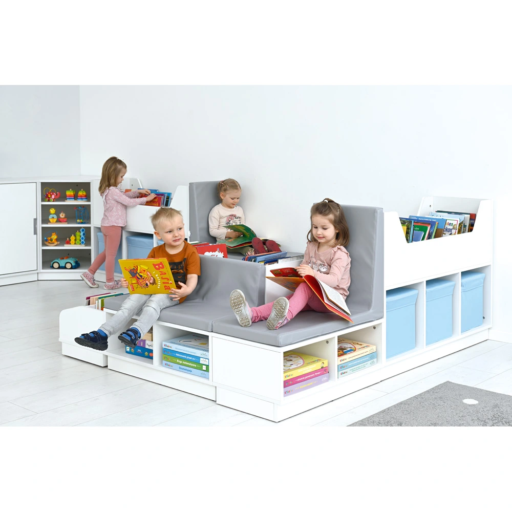 Kinder schmökern und entspannen in einer Leseecke, eingerichtet mit Regalen, Bücherboxen und Schaumstoffsitzen.