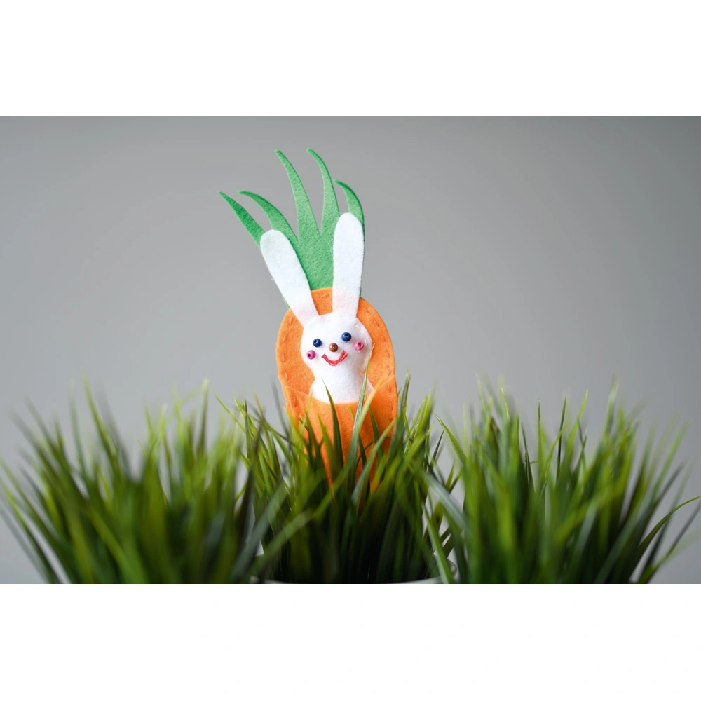 Ein Filz-Osterhase in einer Möhre verschönert einen Blumentopf.
